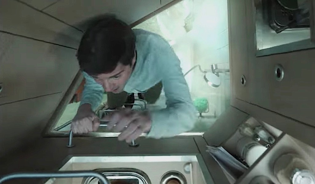 A person climbing through a hatch in a wooden ceiling.