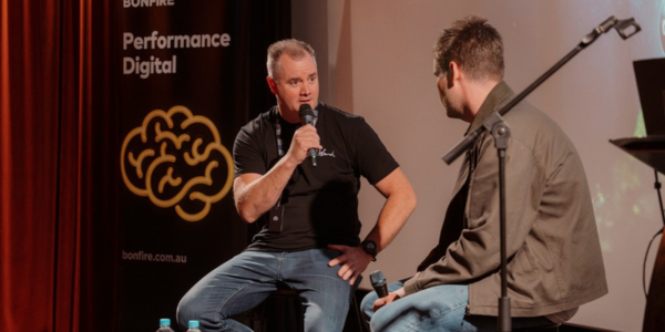 Two people in conversation on stage in front of a Bonfire banner.