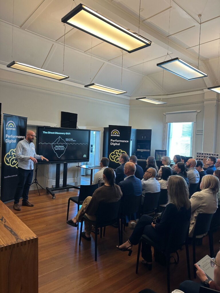 A photo of Matthew Elshaw presenting to a room of marketing professionals and business owners about AI Search Reporting.